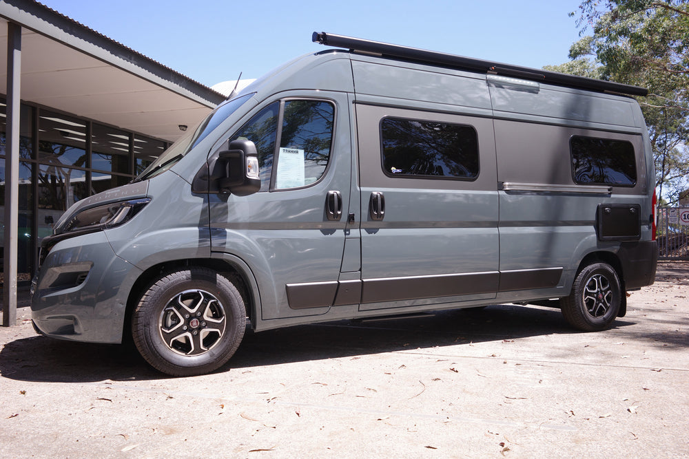 A modern gray camper van parked on a concrete surface during daytime