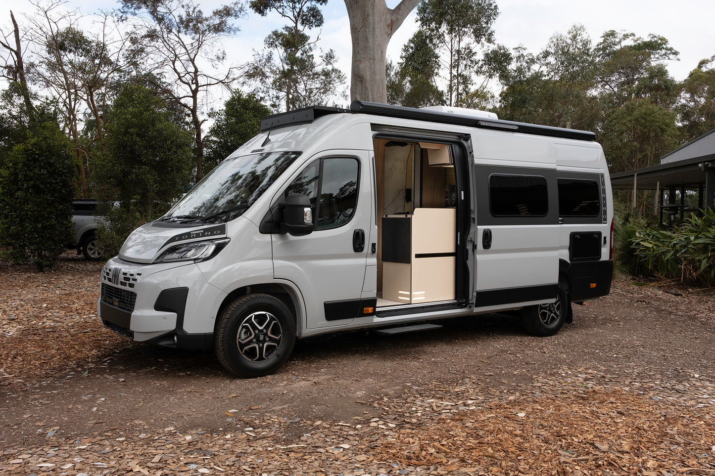 
                  
                    Grey Trakka Torino campervan on Fiat Ducato with sliding door open in bushland
                  
                