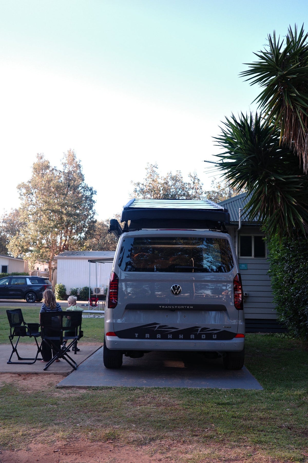 Rear of a Trakkadu campervan with awning out at a caravan park