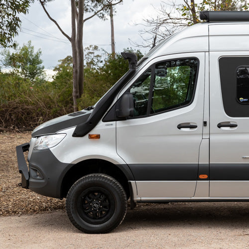 A silver van parked outdoors with a snorkel and off-road tires